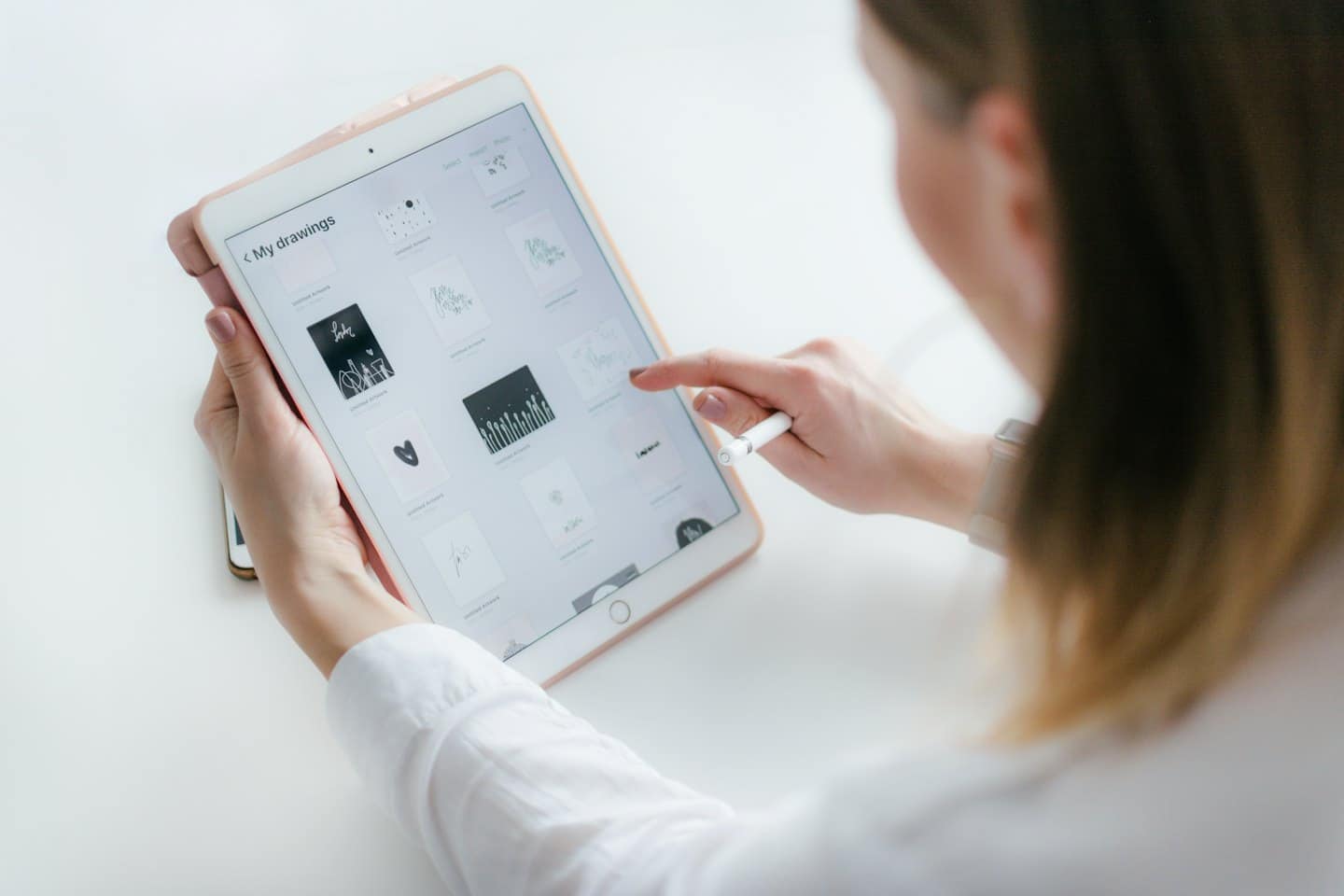 Händer som använder en roséguldplatta för att bläddra i digital konst.